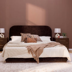 Modern bedroom with dark headboard, beige bedding, and vintage pillows.