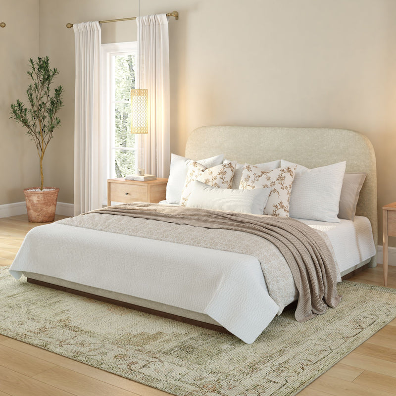 Elegant bedroom interior with well-lit natural light, featuring a cozy bed, beige throw pillows, and neutral decor.