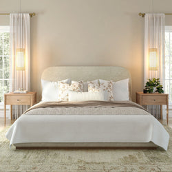 Modern bedroom with a beige upholstered bed, patterned pillows, bedside tables, and elegant lighting for a cozy ambiance.