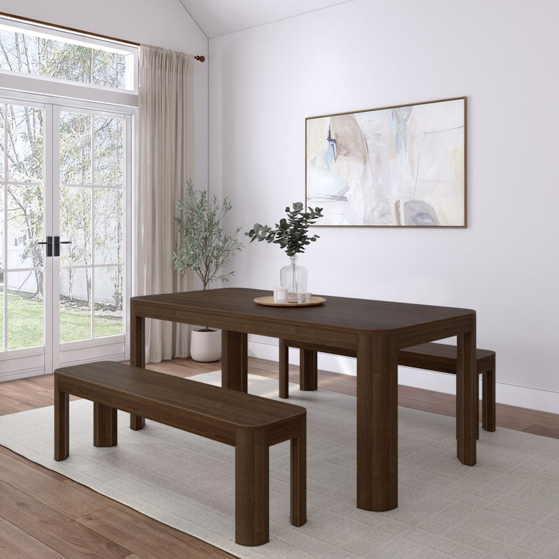 Minimalist dining room with modern dark wood table and benches, featuring a large abstract painting and glass doors offering natural light.