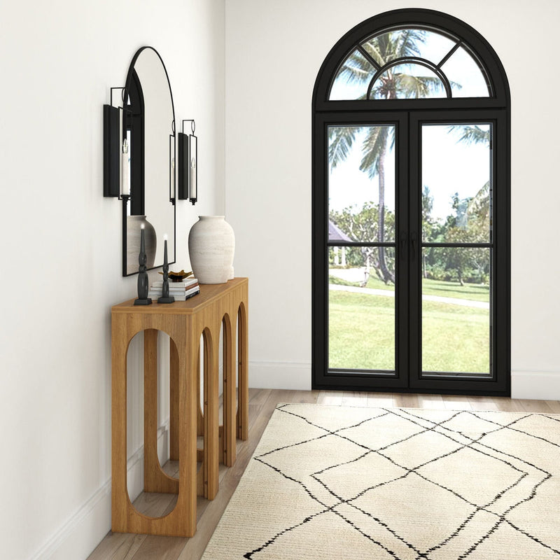 Modern hallway interior with wooden console table, decorative mirror, and elegant arched window overlooking a garden.