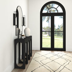 Elegant entryway with modern black console table, decorative vases, and arched mirror beside large arched window with garden view.