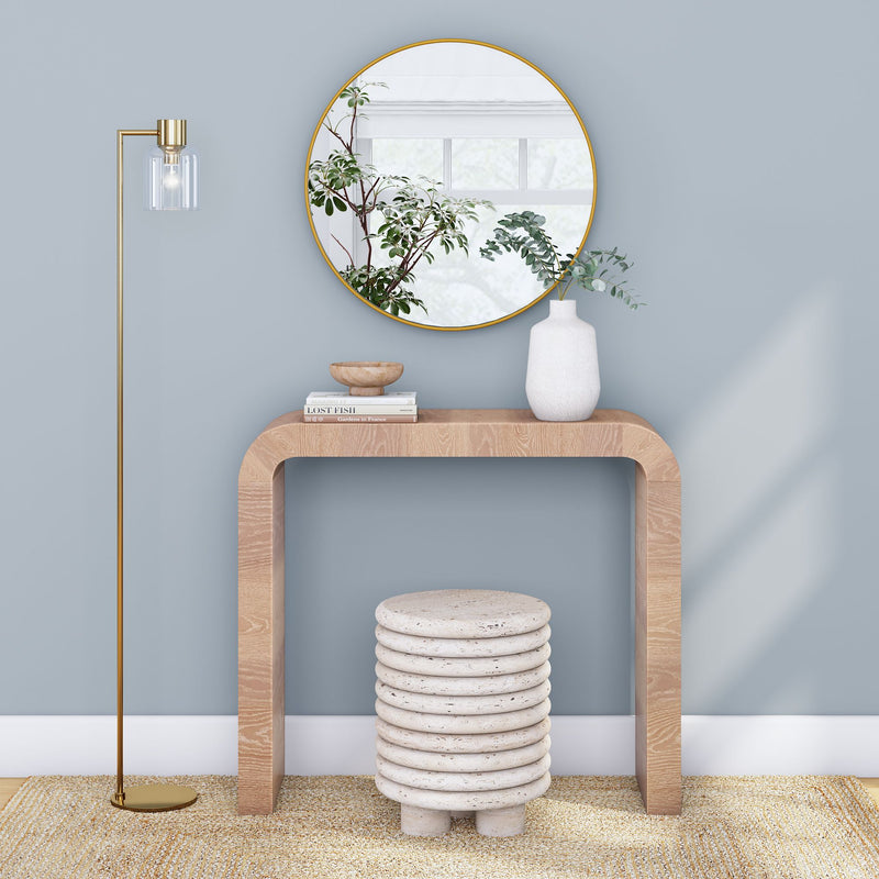 Modern living room interior with decorative console table, round mirror, contemporary floor lamp, and unique stone stool on beige rug.