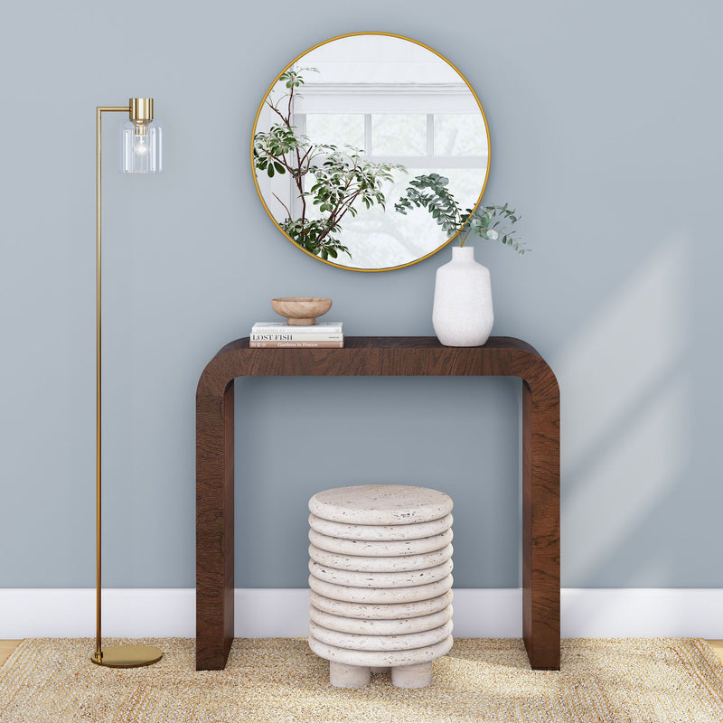 Modern interior design with wooden console table, ceramic stool, round mirror, and decorative floor lamp against a light blue wall.