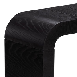Close-up of black oak wood console table corner with rounded edge and visible wood grain, modern minimalist furniture detail