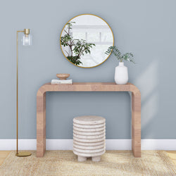 Minimalist entryway: curved natural wood console table, round gold mirror, white vase with eucalyptus, glass floor lamp, textured stool