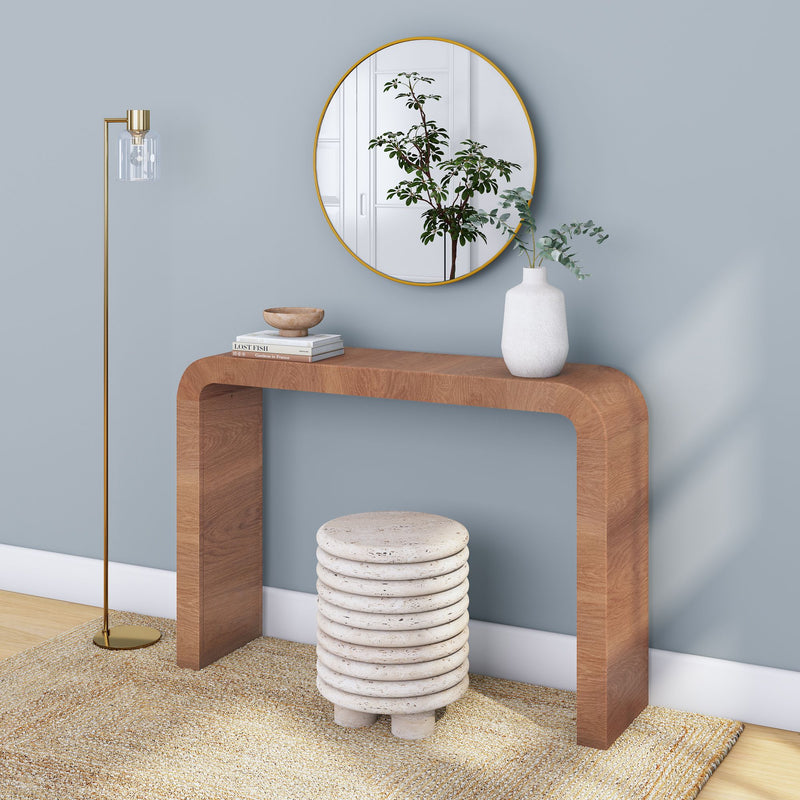 Modern minimalist entryway with curved wooden console table, round gold mirror, ceramic vase, gold floor lamp and textured stone stool