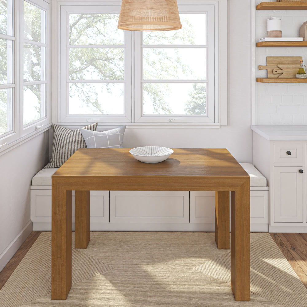 Cozy kitchen nook with wooden dining table, white dish, and built-in bench seating near large windows.