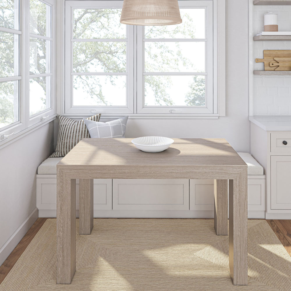 Cozy dining nook with wooden table and cushioned bench seating near large windows.