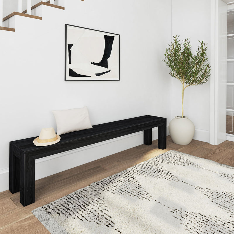 Modern minimalistic hallway with a black bench, hat, abstract artwork, potted plant, and textured rug.