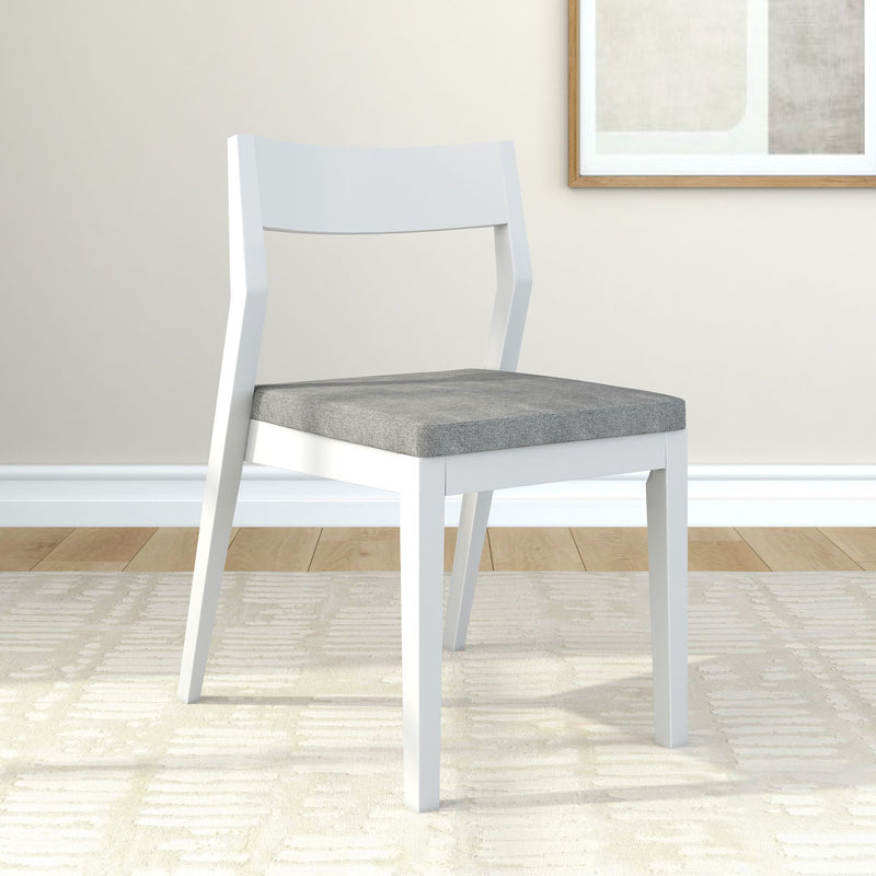 Modern white wooden chair with gray cushion in minimalist living room setting.