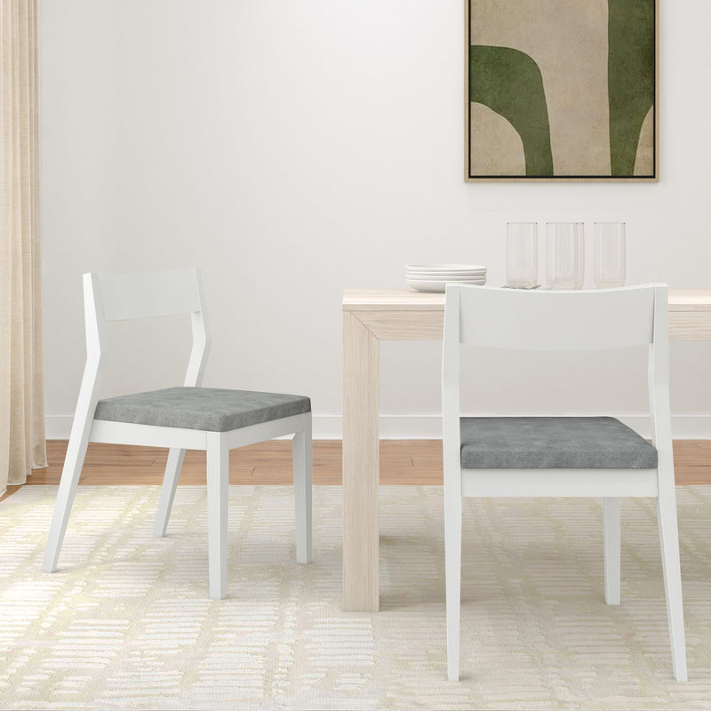 Modern minimalist dining room with white wooden chairs, light wooden table, and abstract art on the wall.