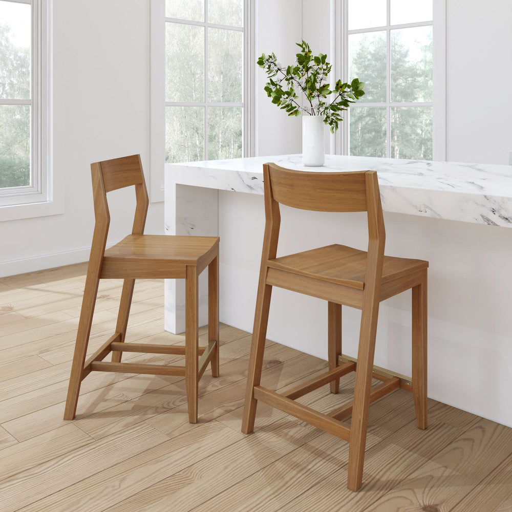 Modern wooden bar stools at a marble kitchen counter in a bright, minimalist interior.