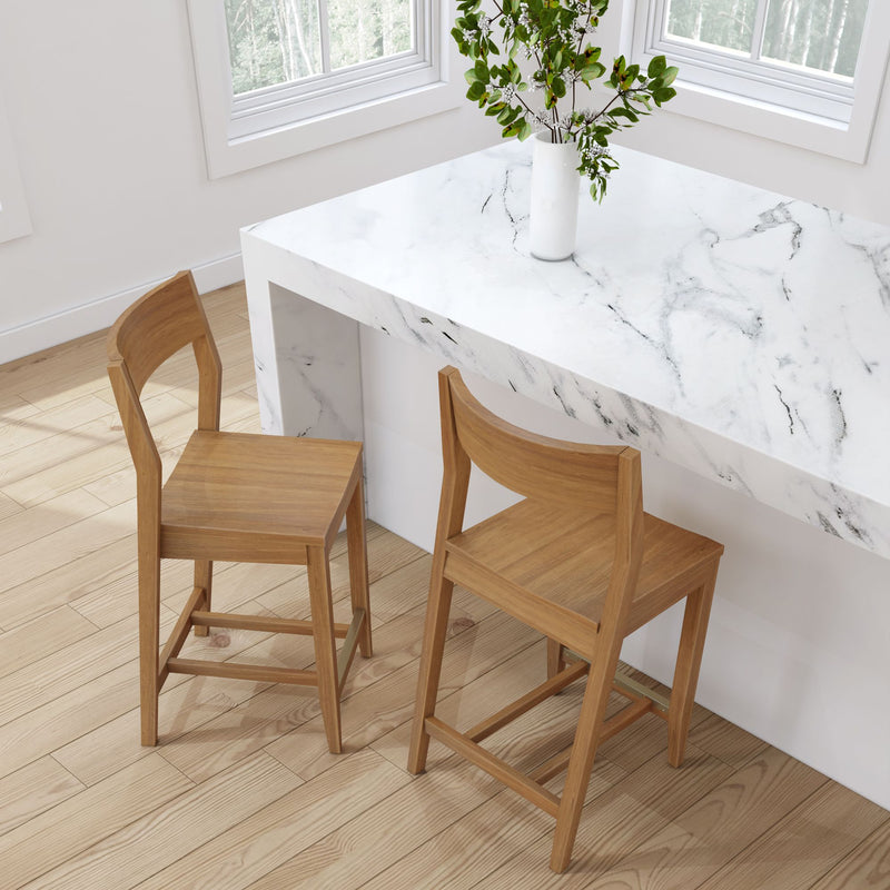 Modern kitchen with wooden bar stools and white marble counter with decorative plant.
