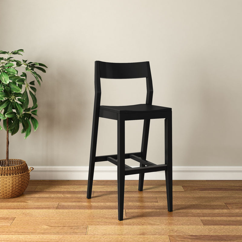 Black wooden bar stool on polished hardwood floor with indoor plant.