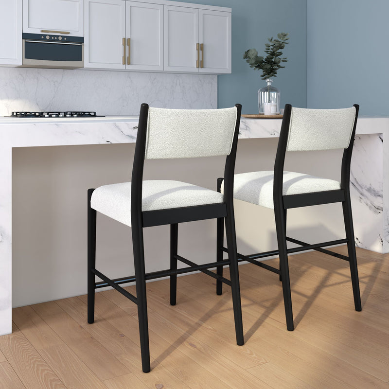 Modern black-frame counter stools with white upholstered seats and backs at a marble kitchen island in a contemporary kitchen with white cabinets, blue accent wall, and light wood floors