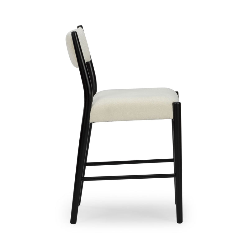Side view of modern black metal-frame bar stool with cream upholstered seat and back on white background