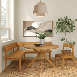 Modern Scandinavian dining nook with round light-wood table, corner bench and chair, pendant lamp, abstract wall art, potted plant and textured rug