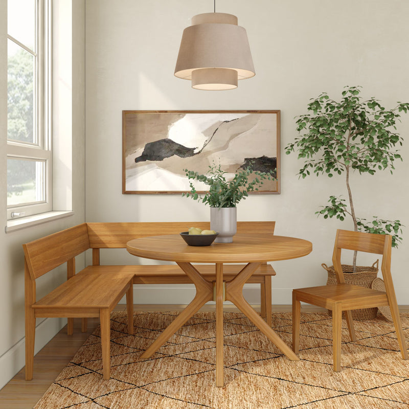 Modern Scandinavian dining nook with round light-wood table, corner bench and chair, pendant lamp, abstract wall art, potted plant and textured rug