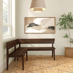 L-shaped dark wood corner bench in a bright modern entryway with abstract framed art, woven jute rug, pendant light, and potted ficus plant