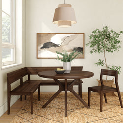 Cozy modern dining nook with dark walnut round pedestal table, wooden corner bench and chair, neutral pendant light, abstract wall art, potted indoor plant and jute area rug by a bright window