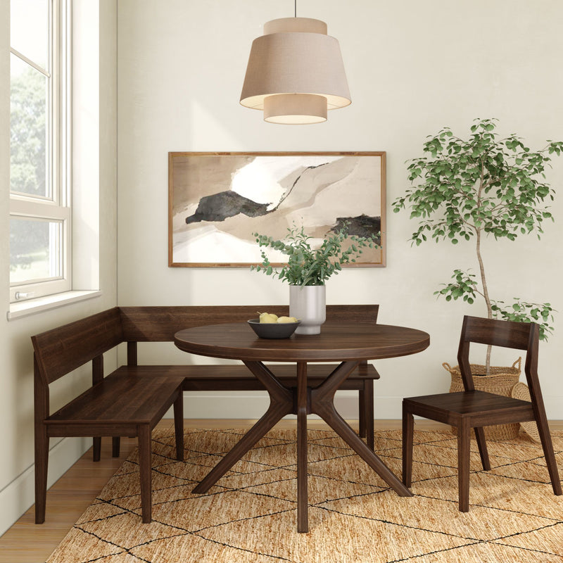 Cozy modern dining nook with dark walnut round pedestal table, wooden corner bench and chair, neutral pendant light, abstract wall art, potted indoor plant and jute area rug by a bright window