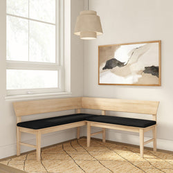 Scandinavian-style light wood L-shaped corner bench with black cushions in a minimalist breakfast nook with pendant lamp, abstract wall art and jute rug