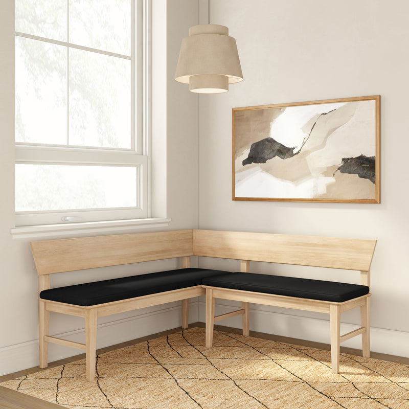 Scandinavian-style light wood L-shaped corner bench with black cushions in a minimalist breakfast nook with pendant lamp, abstract wall art and jute rug