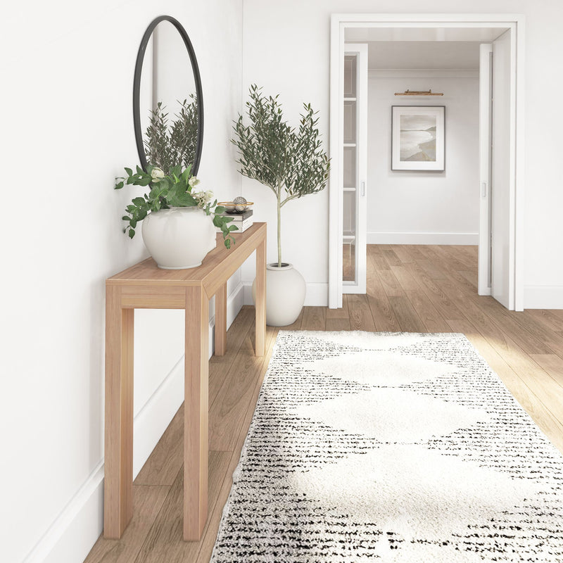 Modern minimalist entryway with wooden console table, decorative mirror, and potted plants.