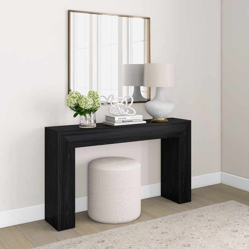 Modern foyer design with black console table, decorative lamp, mirror, and white stool.