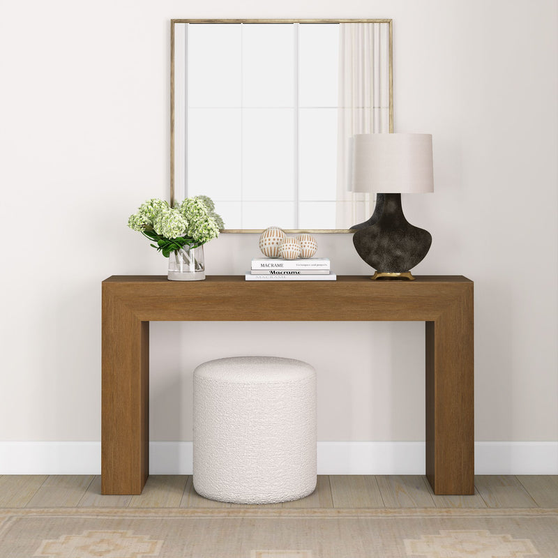 Modern interior design with wooden console table, round mirror, decorative vase, lamp, and white ottoman.
