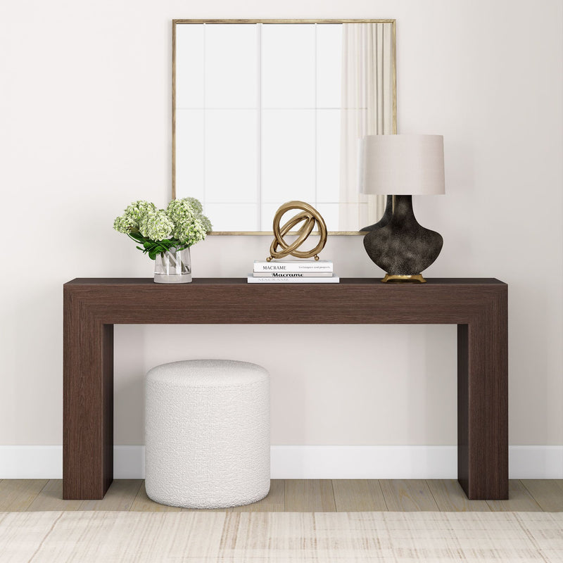 Modern living room decor with a brown console table, mirror, lamp, vase of flowers, and decorative objects.