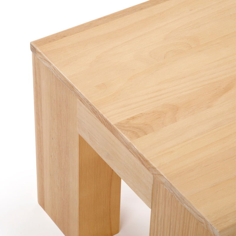 Modern minimalist light wood table with square legs displayed against a white background.