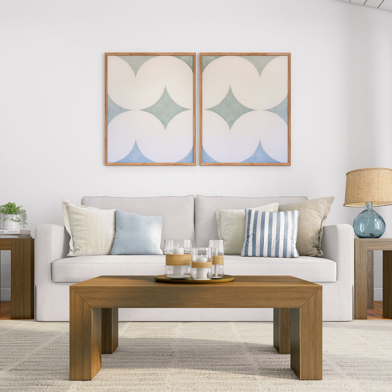 Modern living room with a white sofa, decorative pillows, abstract wall art, wooden coffee table, and table lamp.