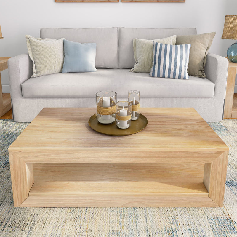 Modern living room with beige couch, decorative pillows, wooden coffee table, and candles in glass holders.