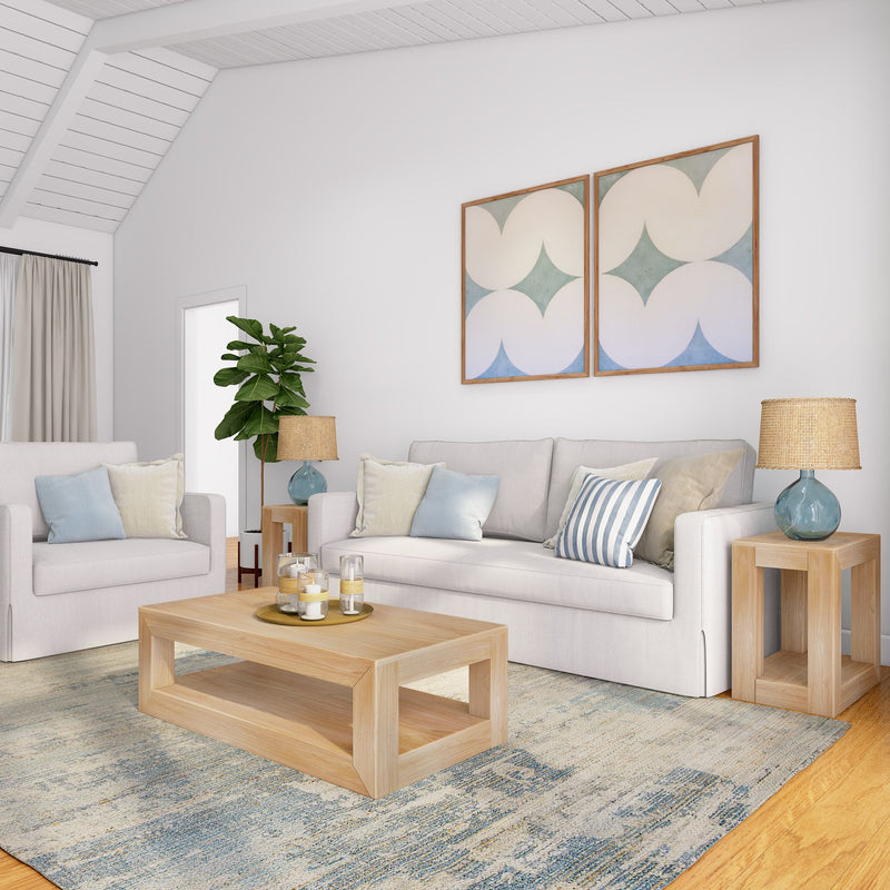 Cozy minimalist living room with a white sofa, wooden coffee table, abstract wall art, and decorative pillows.