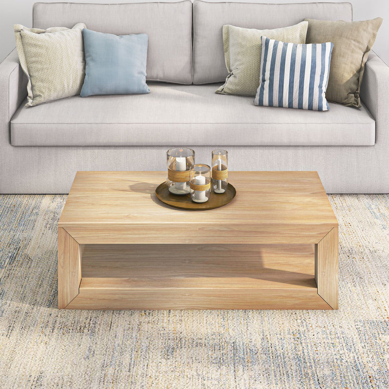 Modern living room with a beige sofa, decorative pillows, and a wooden coffee table featuring a tray with candles.
