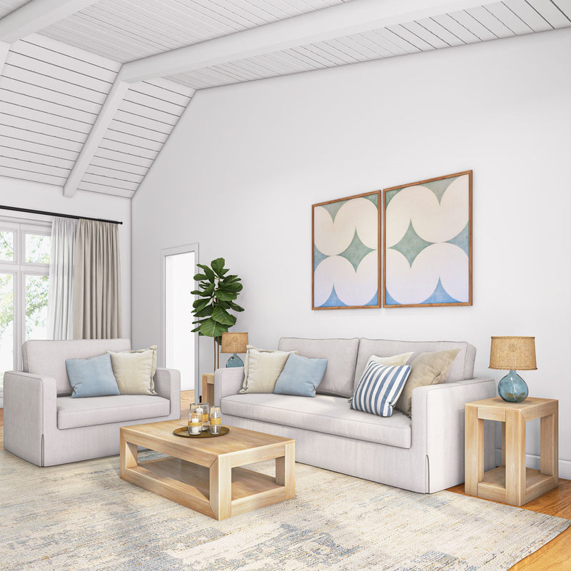 Modern living room with cream sofas, wooden coffee table, decorative pillows, abstract wall art, and natural light.