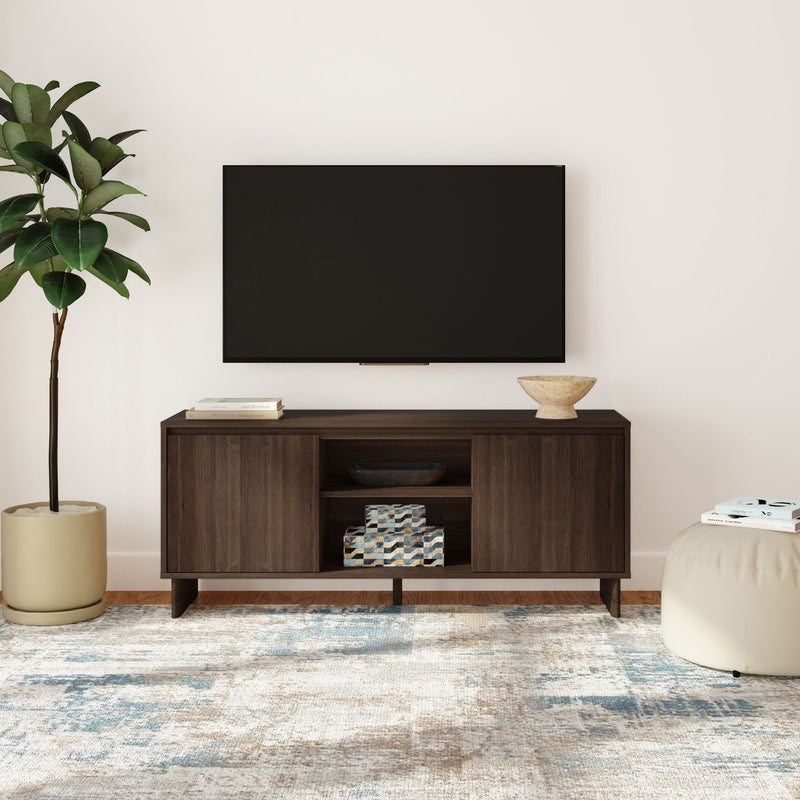 Modern living room with wall-mounted TV over dark wood media console, abstract area rug, potted plant and neutral decor