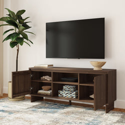 Dark walnut wooden TV console with open cubbies and cabinet doors under wall-mounted flat-screen TV, styled with decorative bowls, storage boxes, potted plant, and patterned rug