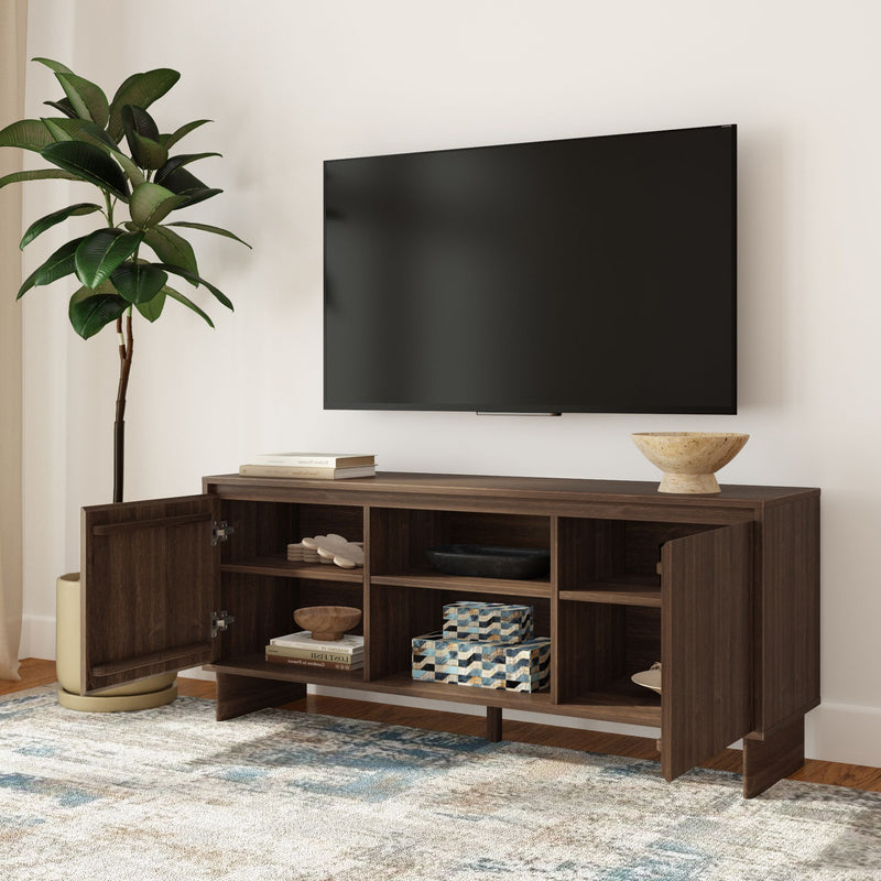 Dark walnut wooden TV console with open cubbies and cabinet doors under wall-mounted flat-screen TV, styled with decorative bowls, storage boxes, potted plant, and patterned rug