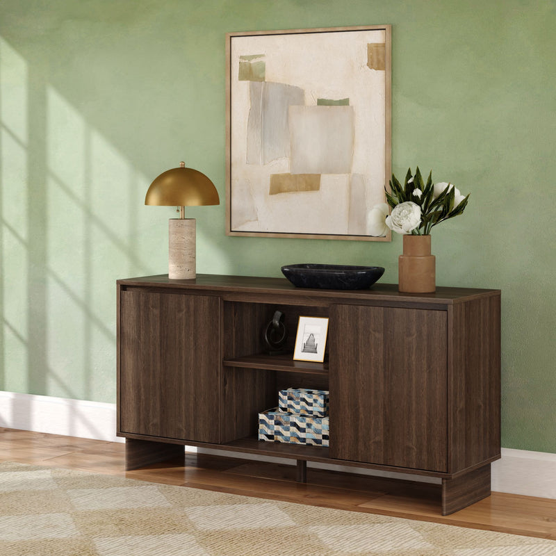 Modern dark wood sideboard console table in living room/entryway against sage green wall, styled with abstract framed art, brass dome lamp, black bowl, terracotta vase with white flowers and patterned storage boxes