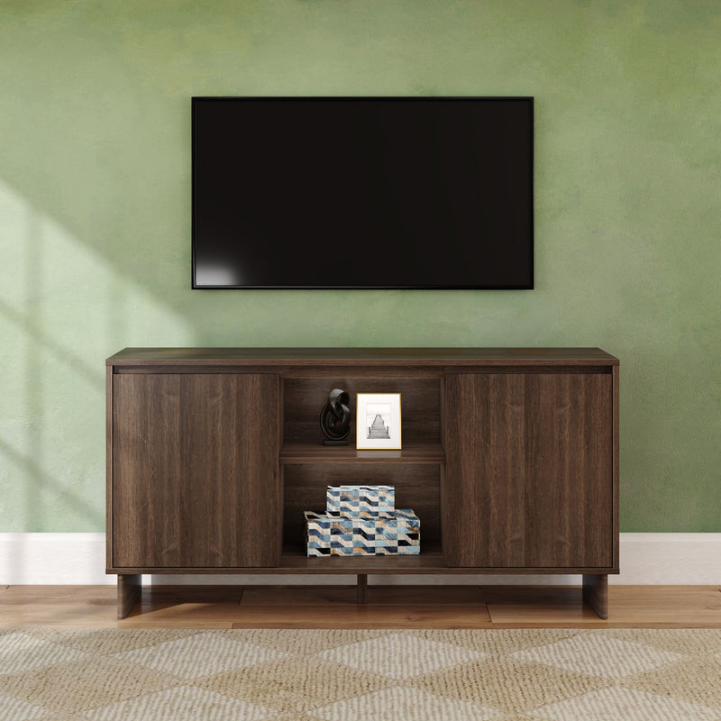 Modern wooden TV console and media cabinet under a wall-mounted flat-screen TV on a green accent wall in a living room with framed photo, decorative sculpture, patterned storage boxes, hardwood floor and area rug