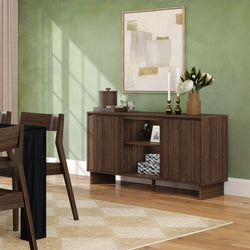 Modern dining room with walnut wooden sideboard and storage cabinet against a green accent wall, abstract artwork, vase with white flowers, brass candlesticks and hardwood floors