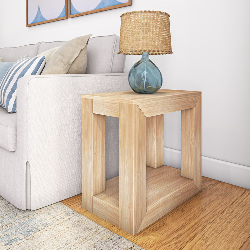 Wooden end table with modern design holding a blue glass lamp, positioned next to a beige sofa in a cozy living room setting.