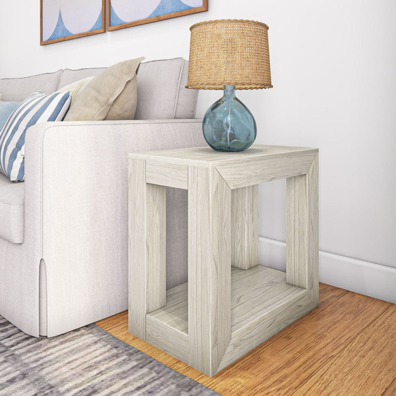 Contemporary light wood end table with modern design, featuring a stylish blue glass lamp, positioned beside a beige sofa in a cozy living room setting.