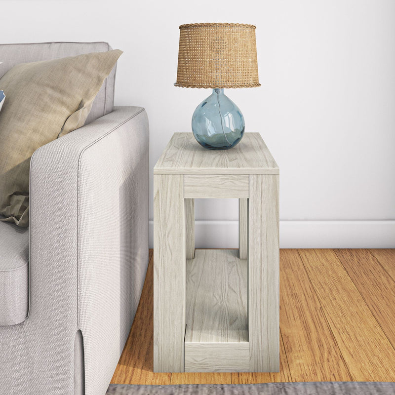 Side table with woven lampshade and glass lamp in modern living room setting.