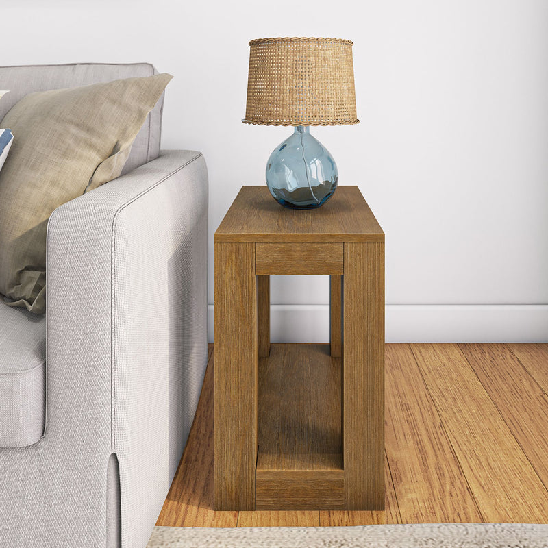 Rustic wooden side table with a blue glass lamp and wicker shade beside a gray sofa in a cozy living room.