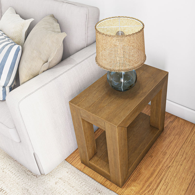 Wooden side table with a glass lamp and sofa, modern living room decor.