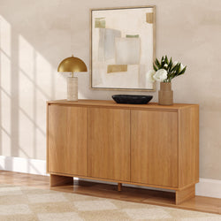 Modern oak console table sideboard in neutral living room, styled with brass dome lamp, black marble bowl, ceramic vase of white peonies, and abstract framed art